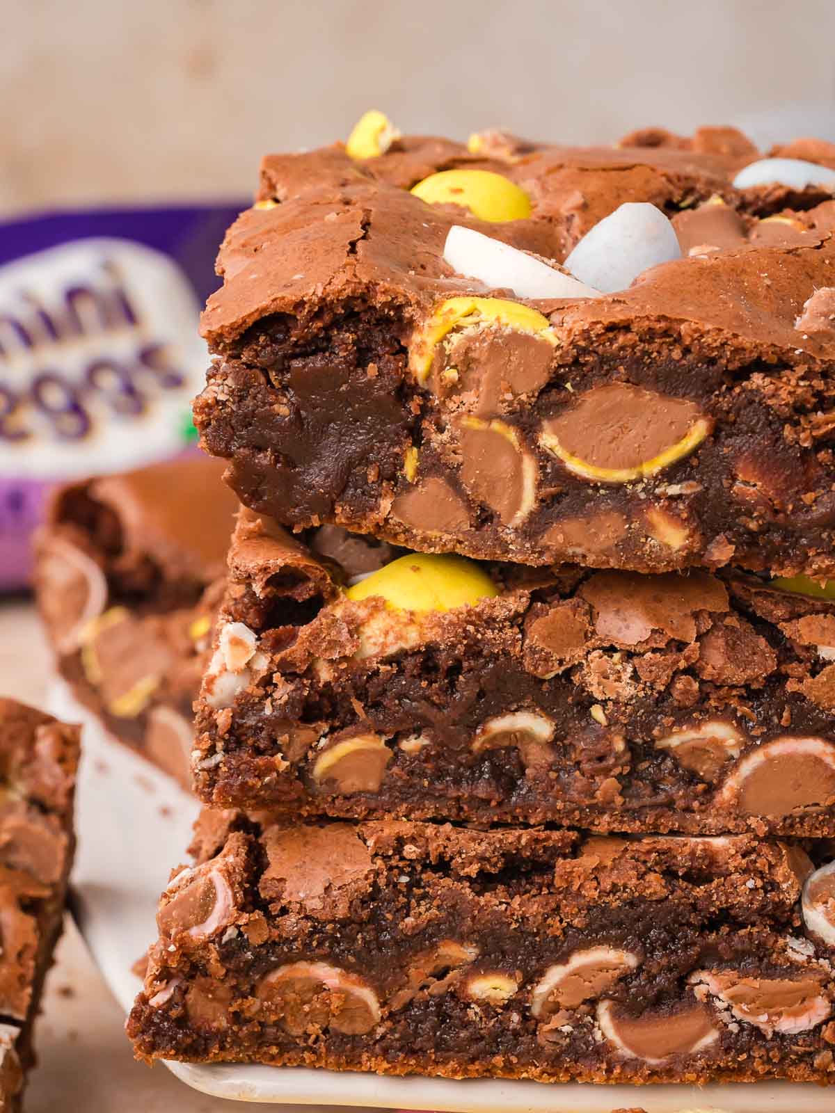 Stack of fudgy Cadbury egg brownies with mini eggs baked into the chocolate layers.