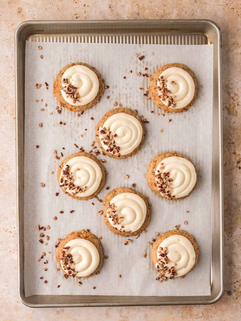 Carrot cake cookies with cream cheese frosting and chopped pecans sprinkled on top.