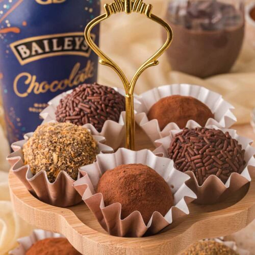 Chocolate Baileys truffles in paper cups with cocoa powder and chocolate sprinkle coatings on a dessert stand.
