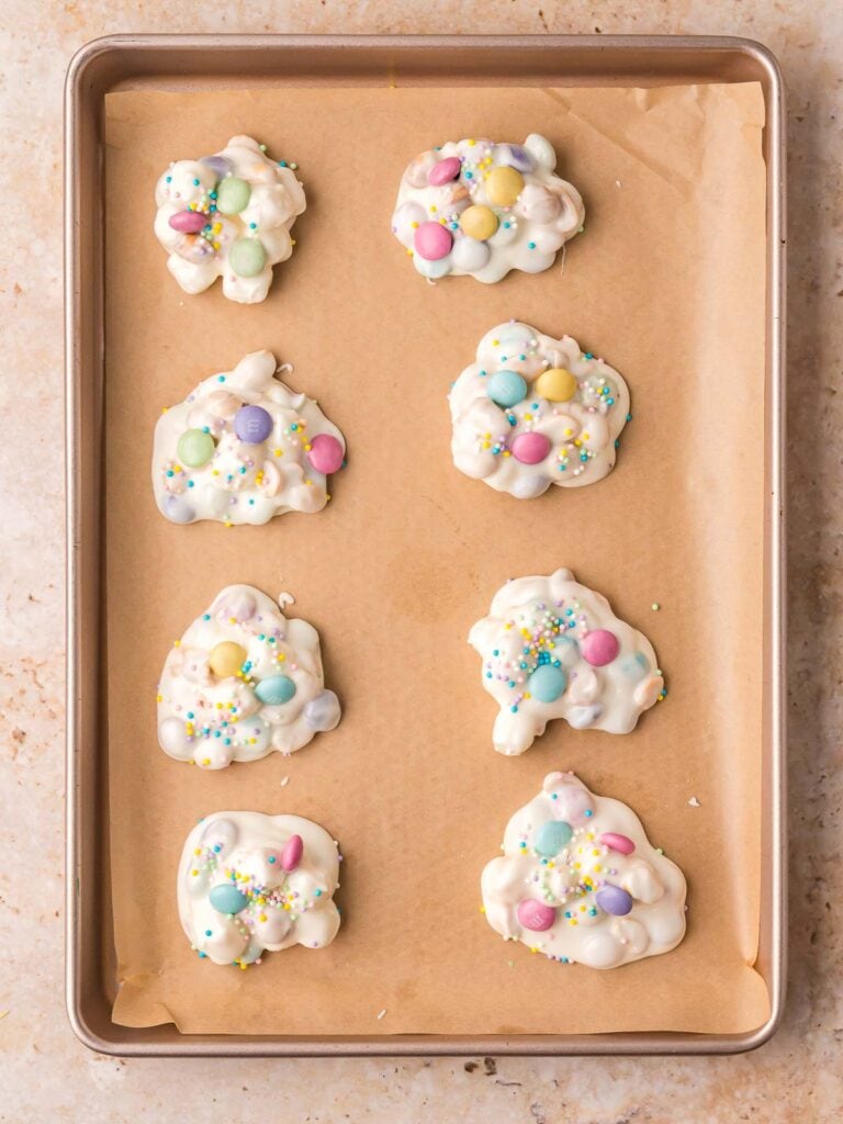 Easter candy clusters scooped onto a parchment lined baking sheet before setting.