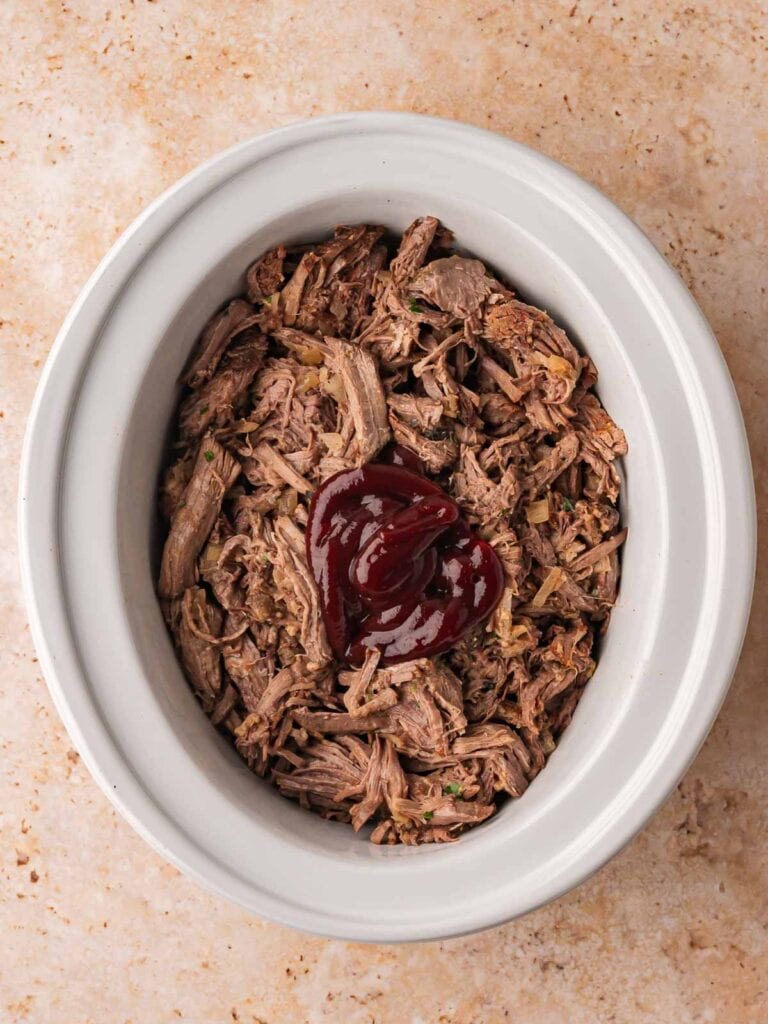 Shredded beef in slow cooker before mixing BBQ sauce.