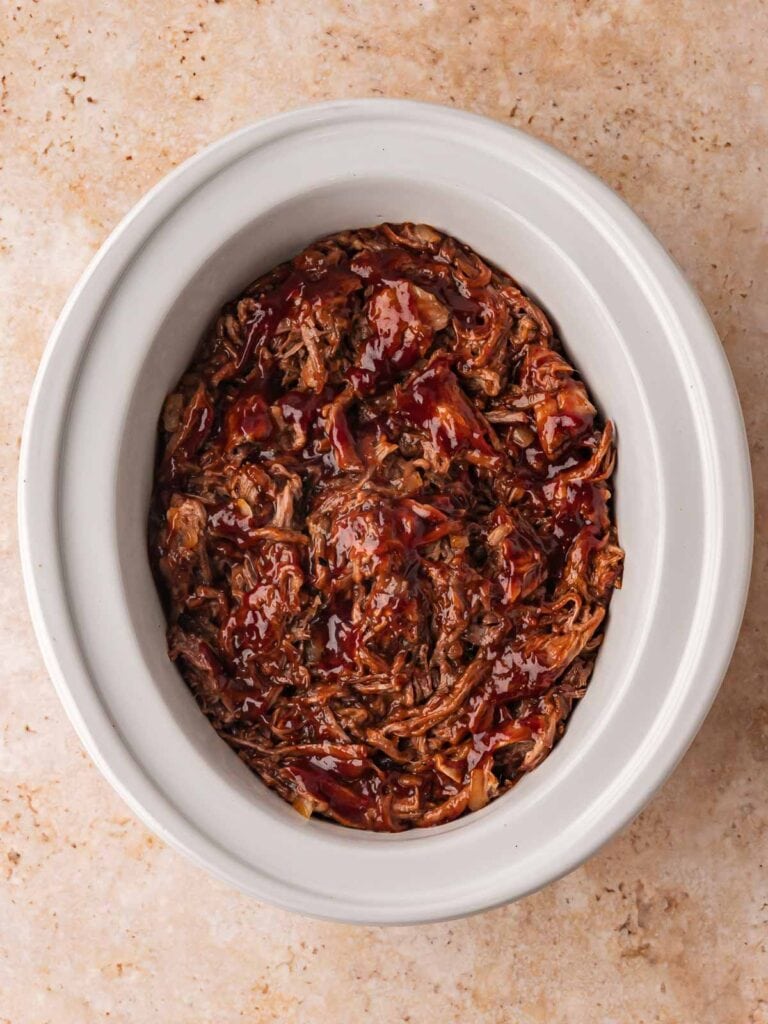 Delicious slow cooker BBQ beef in a white oval dish, perfect for hearty family meals.