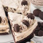 Oreo cheesecake slice being lifted with a spatula, showing thick brownie base and cookies and cream filling.
