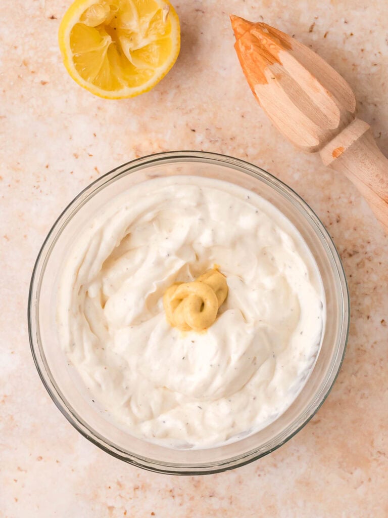 Creamy potato salad dressing with mayonnaise, Dijon mustard, and lemon juice in a bowl.