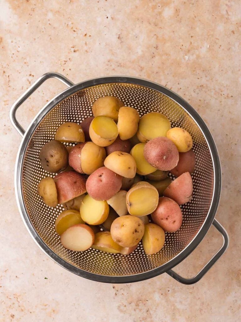 Cooked baby potatoes draining in a colander after boiling.