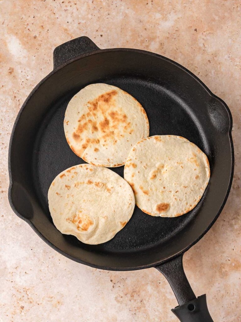Warming the tortillas in a skillet until soft.