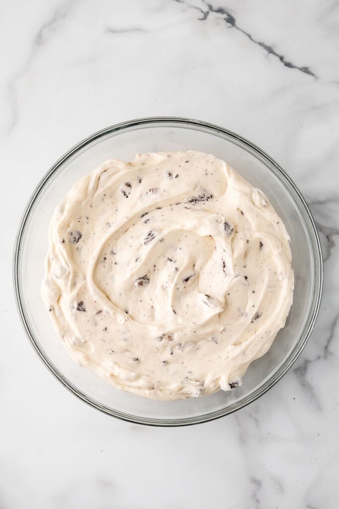 Smooth Oreo cheesecake filling with crushed cookies mixed throughout in a glass bowl.