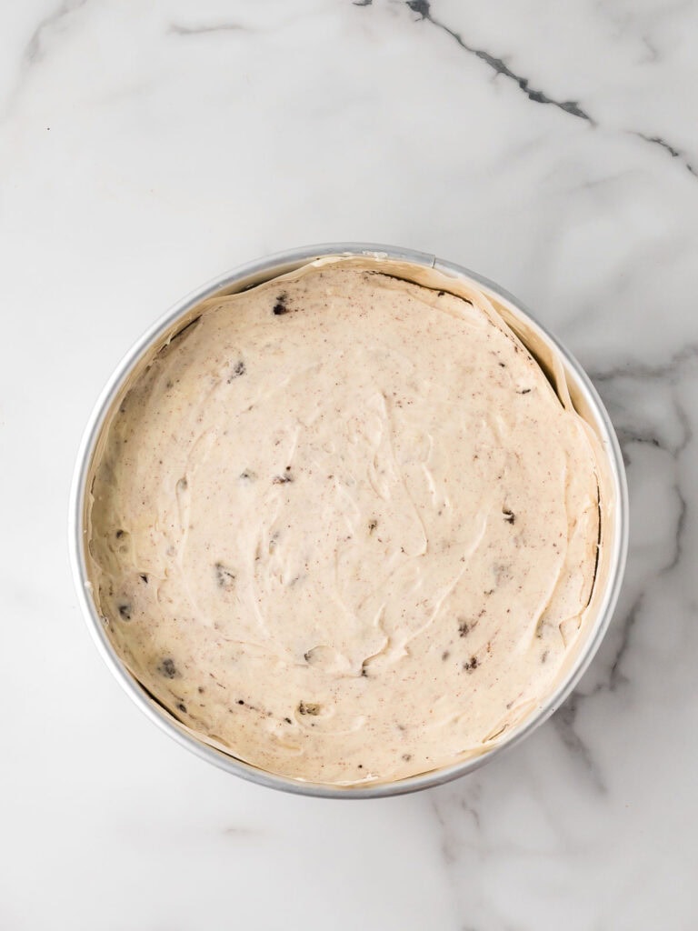 Oreo cheesecake filling spread evenly over the cooled brownie base in a springform pan.