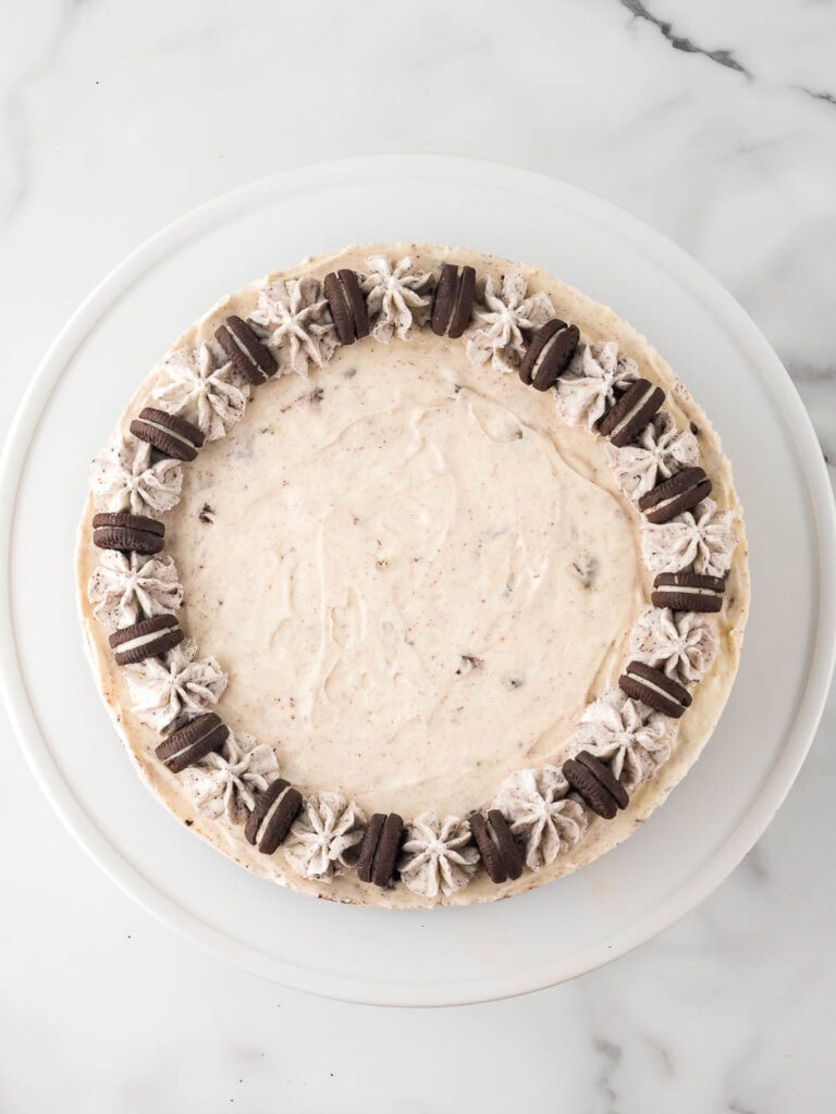 Finished Oreo cheesecake topped with piped Oreo whipped cream and mini Oreos around the edge.