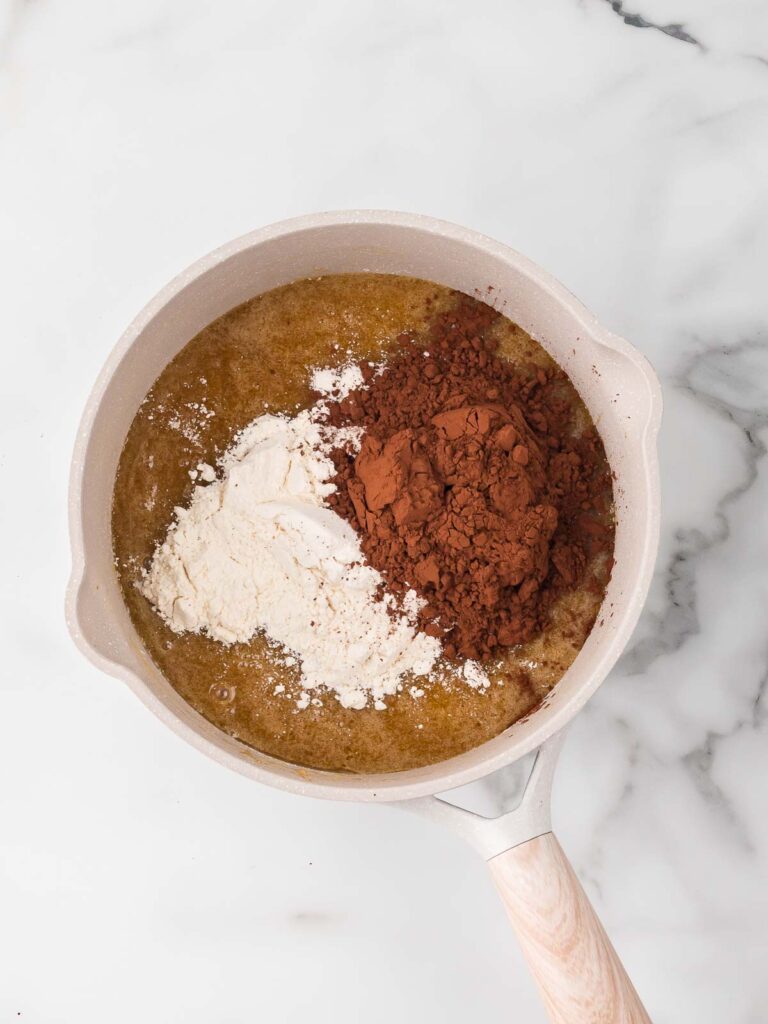 Cocoa powder and flour added to the wet ingredients to make the Oreo cheesecake brownie base batter.