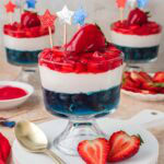 Red White and Blue Dessert Cup served on a white board with fresh strawberries and a gold spoon.