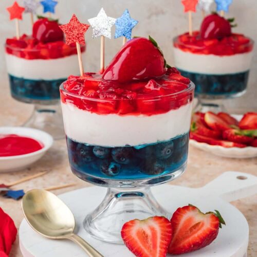 Red White and Blue Dessert Cup served on a white board with fresh strawberries and a gold spoon.
