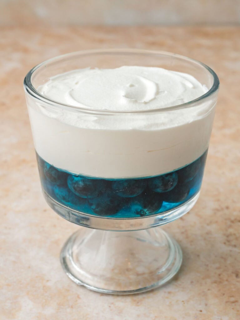 Layered red white and blue dessert cup with blueberry Jello and a thick layer of Cool Whip.