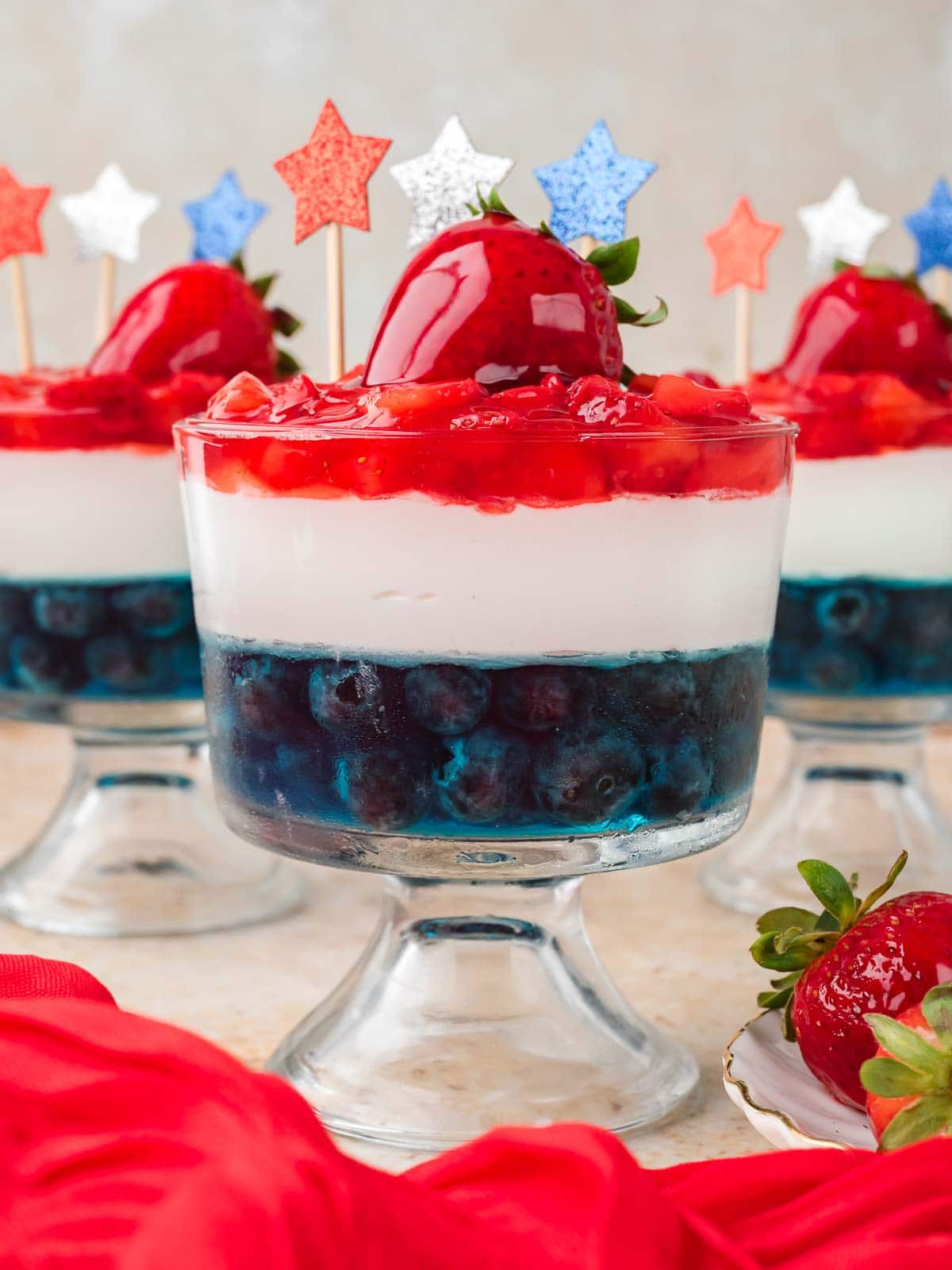Layered Red White and Blue Dessert Cup showing blueberry Jello, Cool Whip, and strawberry topping.