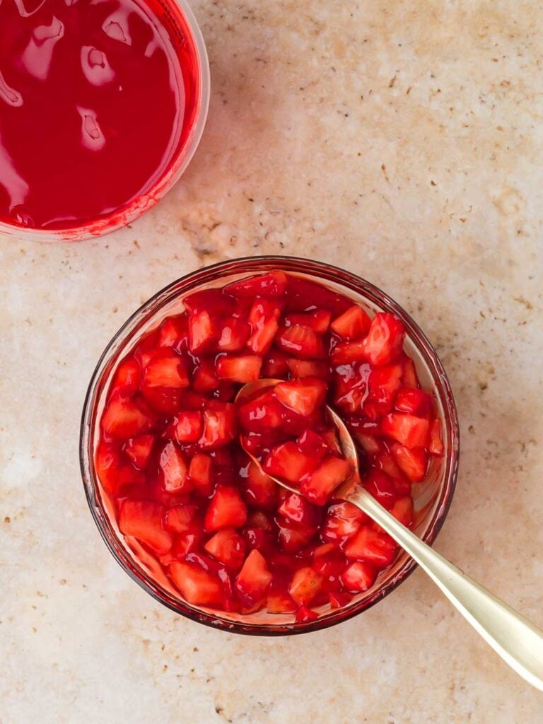 Chopped strawberries mixed with strawberry glaze in a bowl with a spoon.