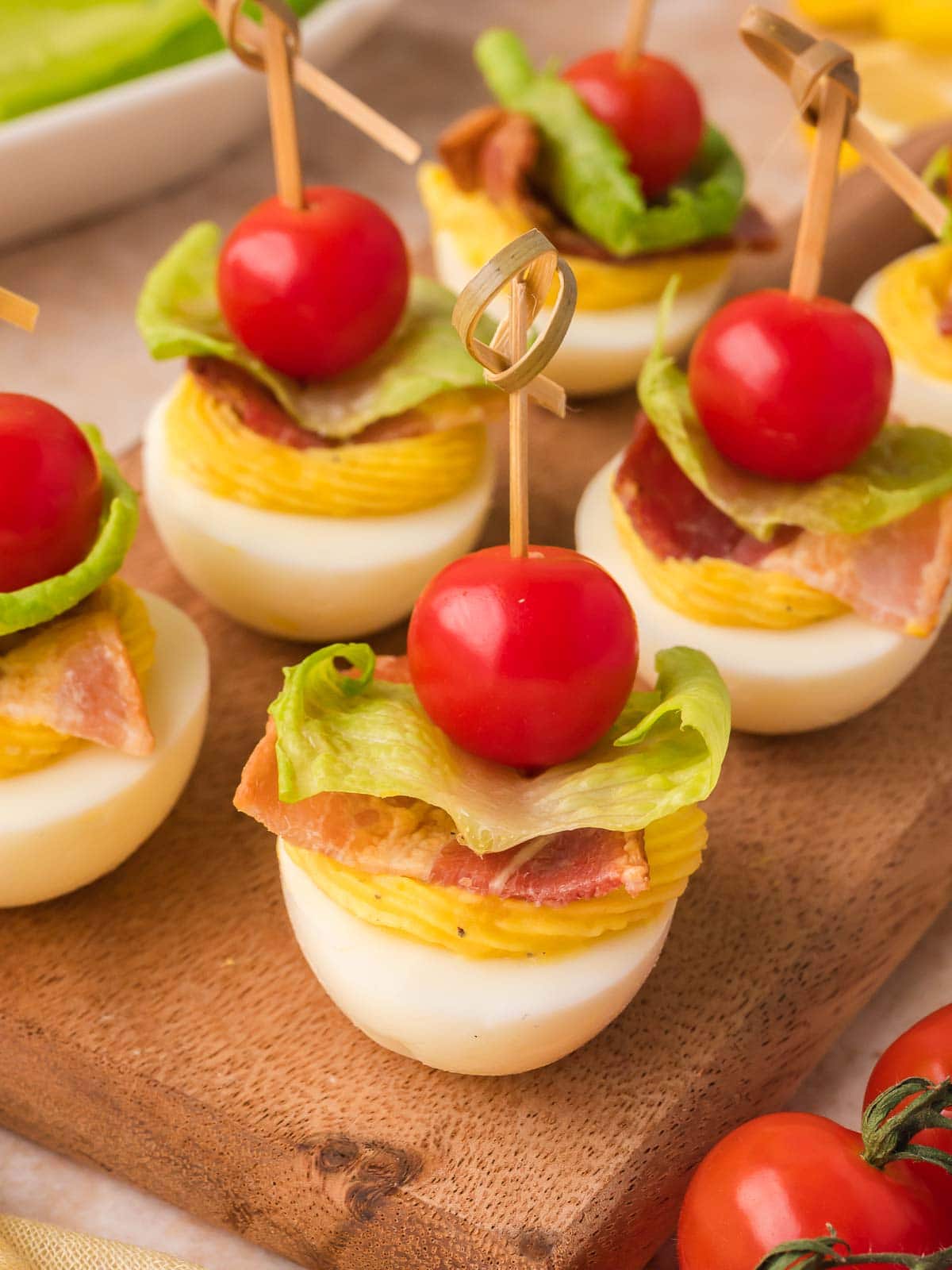 Bacon lettuce tomato deviled eggs served with cherry tomatoes and crispy bacon.