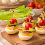 Easy BLT deviled eggs with bacon, romaine lettuce, and cherry tomatoes for summer parties.