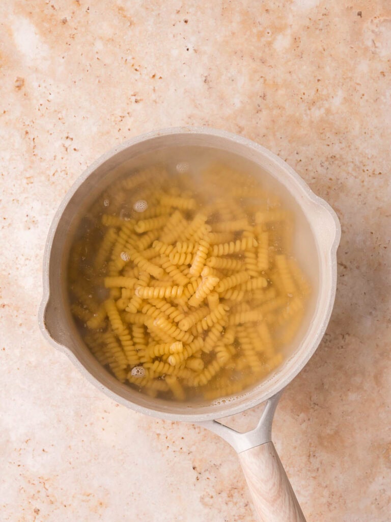Rotini pasta cooking in a pot of boiling water.
