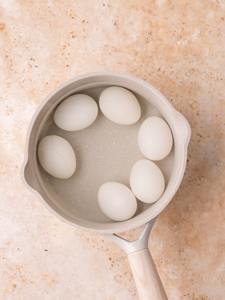 Eggs in a saucepan covered with water before boiling for BLT deviled eggs.