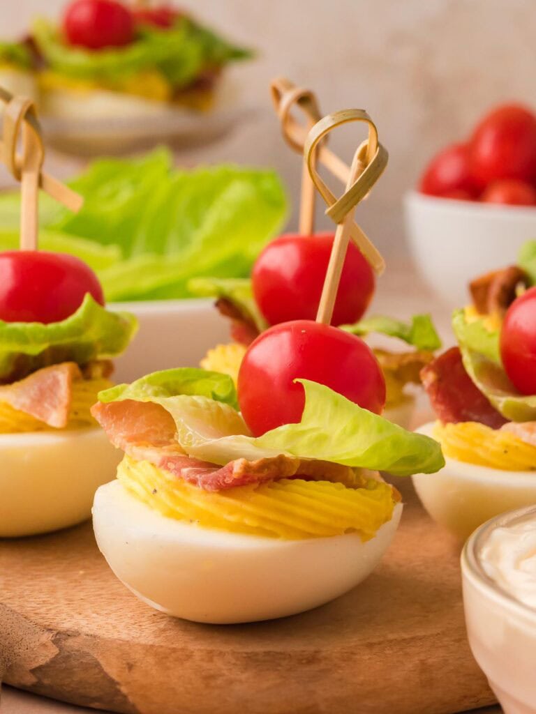 BLT deviled eggs topped with bacon, lettuce, and cherry tomatoes.