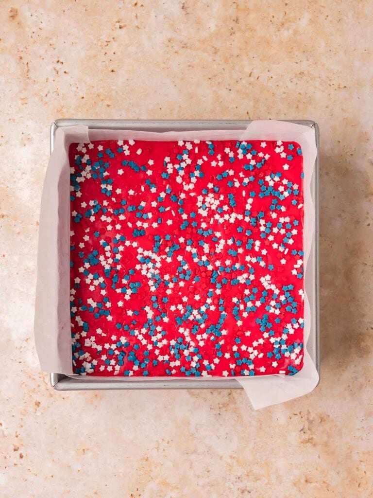 Red white and blue layered fudge topped with patriotic star sprinkles before chilling.