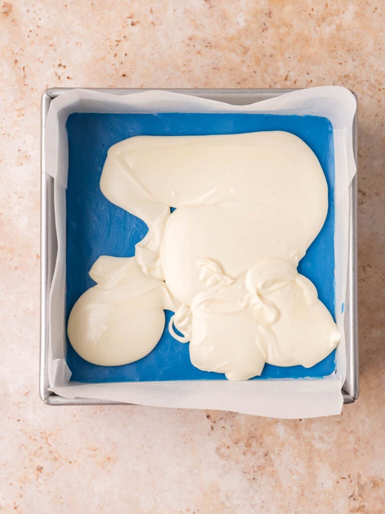 White fudge layer being added over the chilled blue fudge layer.