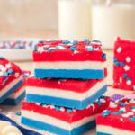 Stacked red white and blue fudge squares decorated with patriotic sprinkles for a 4th of July dessert.