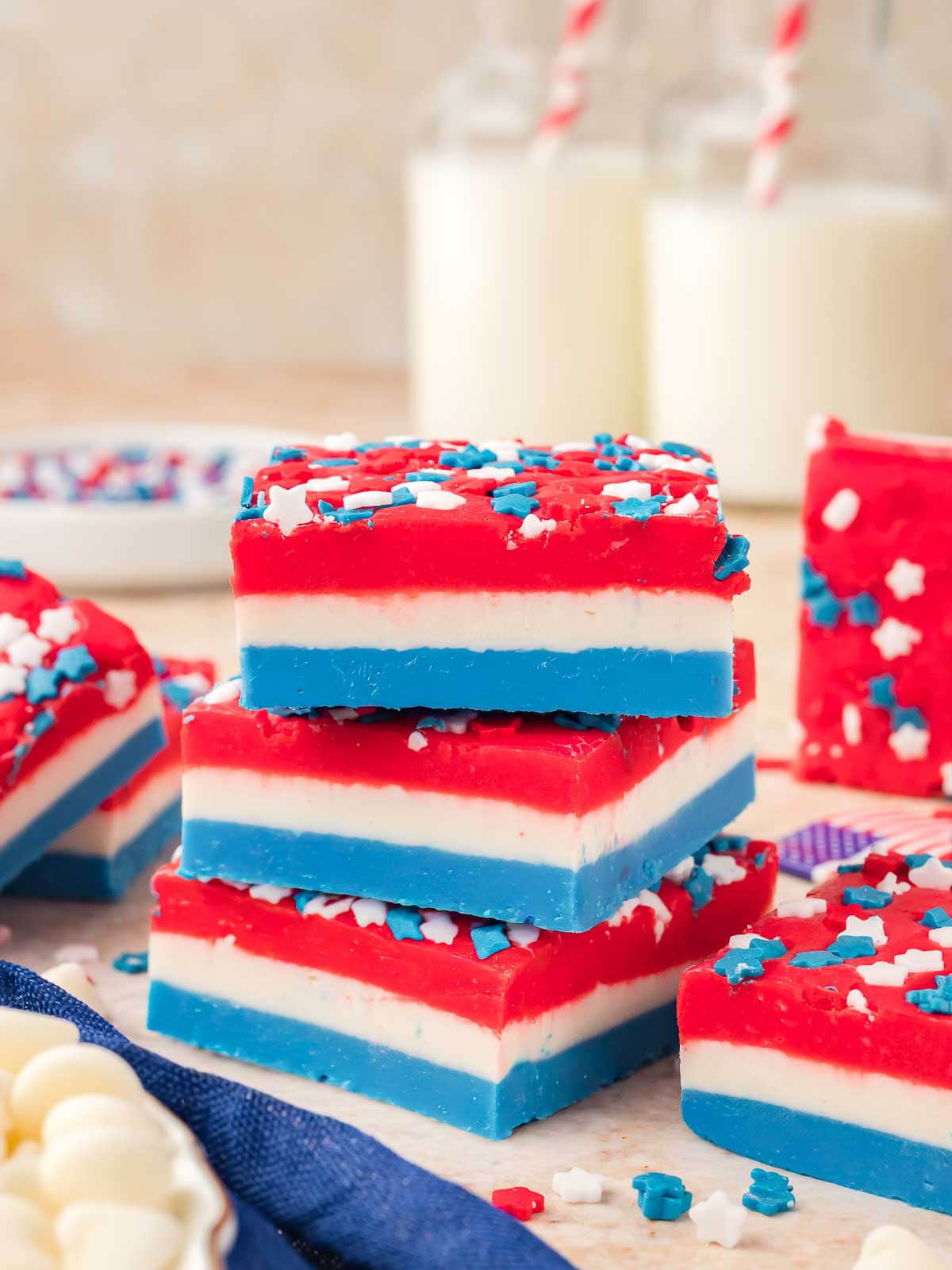 Stacked red white and blue fudge squares decorated with patriotic sprinkles for a 4th of July dessert.