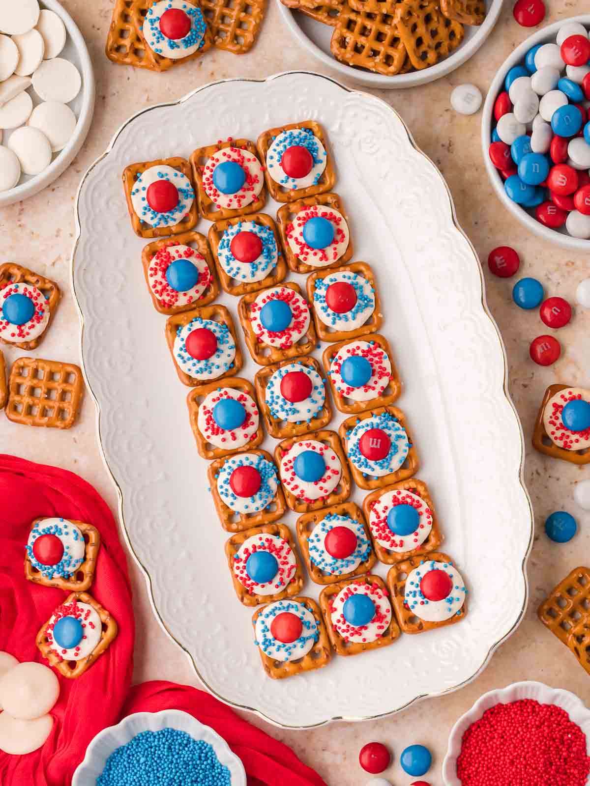 Red White and Blue Pretzel Bites arranged on a serving platter with bowls of M&Ms and sprinkles.