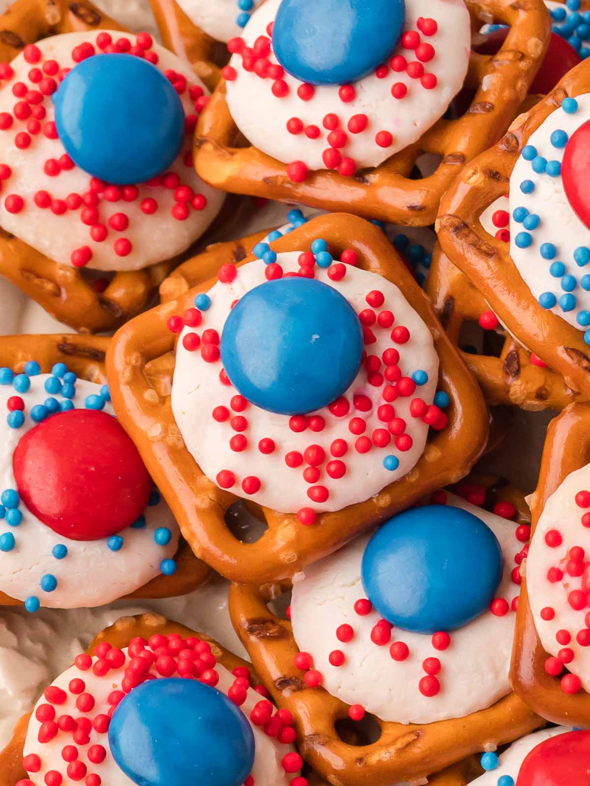 Close up of Red White and Blue Pretzel Bites topped with white chocolate, red and blue M&Ms, and sprinkles.