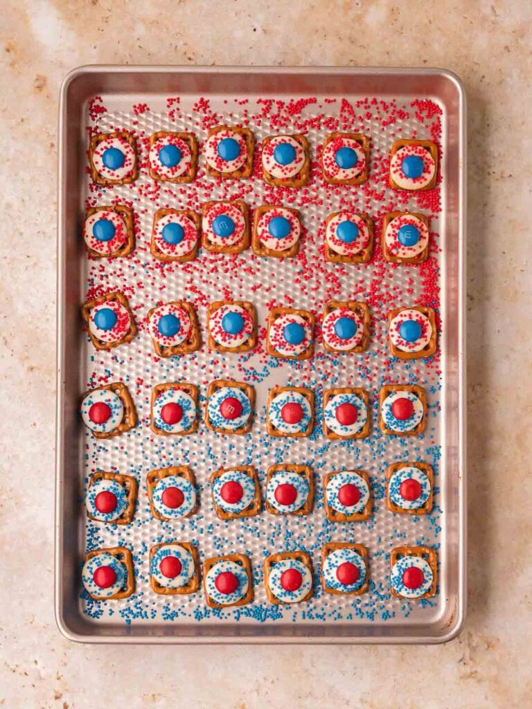 Red White and Blue Pretzel Bites on a baking sheet after decorating with sprinkles and M&Ms.