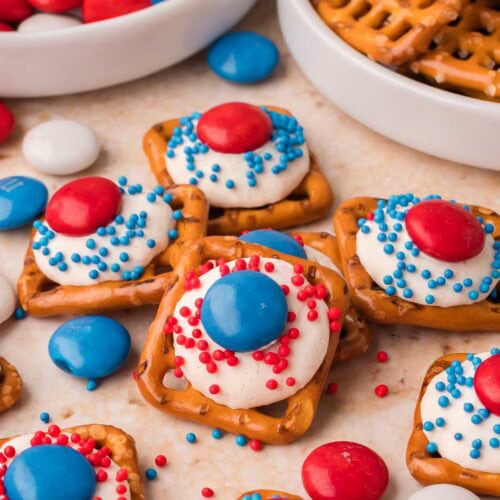 Red White and Blue Pretzel Bites with white chocolate, M&Ms, and sprinkles on a marble surface.
