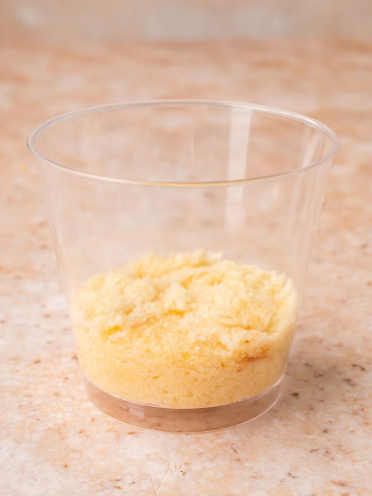 First cake round pressed into the base of a clear plastic dessert cup for dot cakes by Tessie's Table.