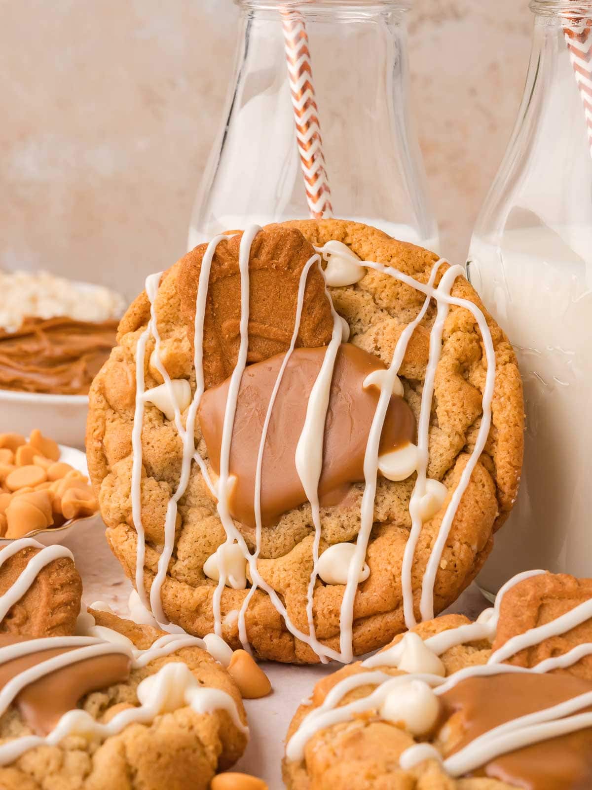Biscoff stuffed white chocolate cookie leaning against a glass milk bottle showing the gooey Biscoff center, by Tessie's Table.