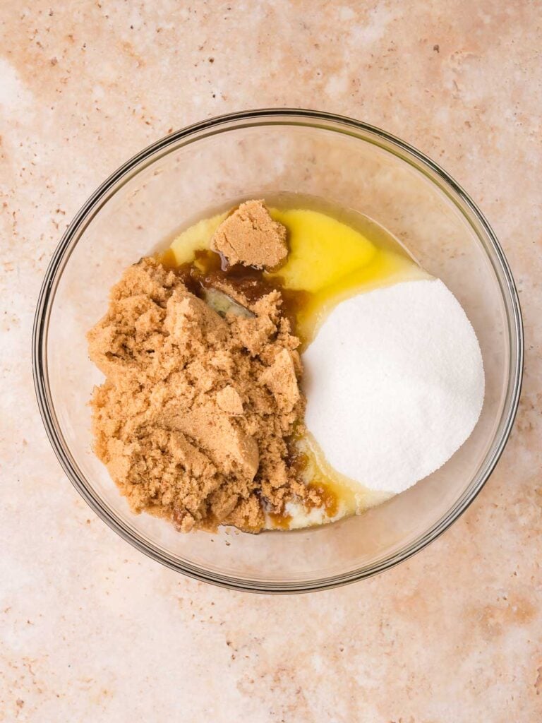 Melted butter, granulated sugar, and brown sugar in a glass bowl to start the strawberry crunch blondies batter.