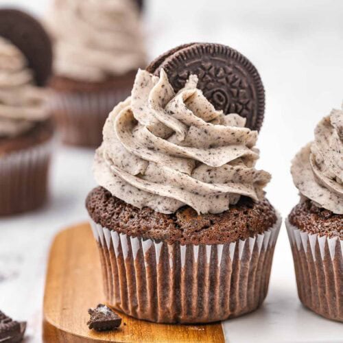 Oreo cupcake with cookies and cream frosting on a wooden board.