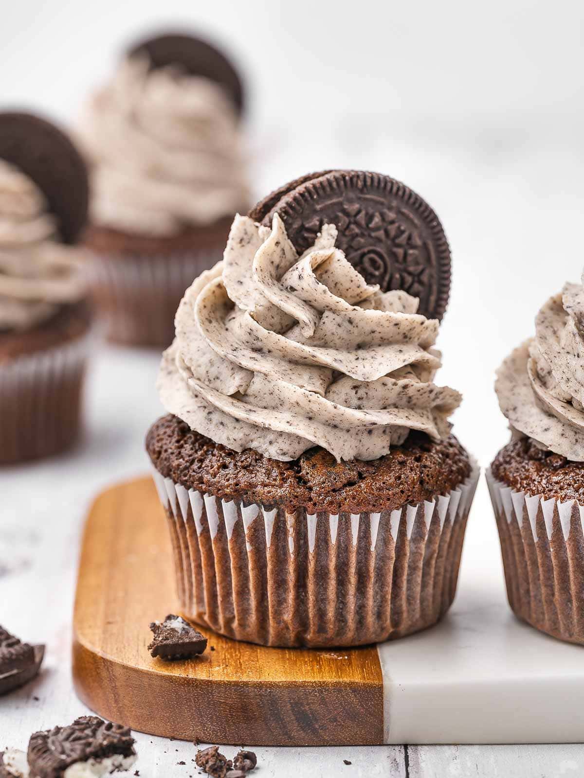 Oreo cupcake with cookies and cream frosting on a wooden board.
