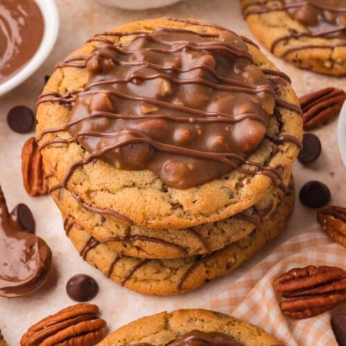 Stack of thick pecan pie cookies with pecan topping and chocolate drizzle by Tessie's Table.