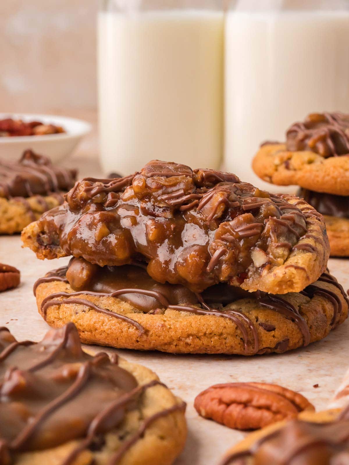 Pecan pie cookies stacked in front of two bottles of milk by Tessie's Table.