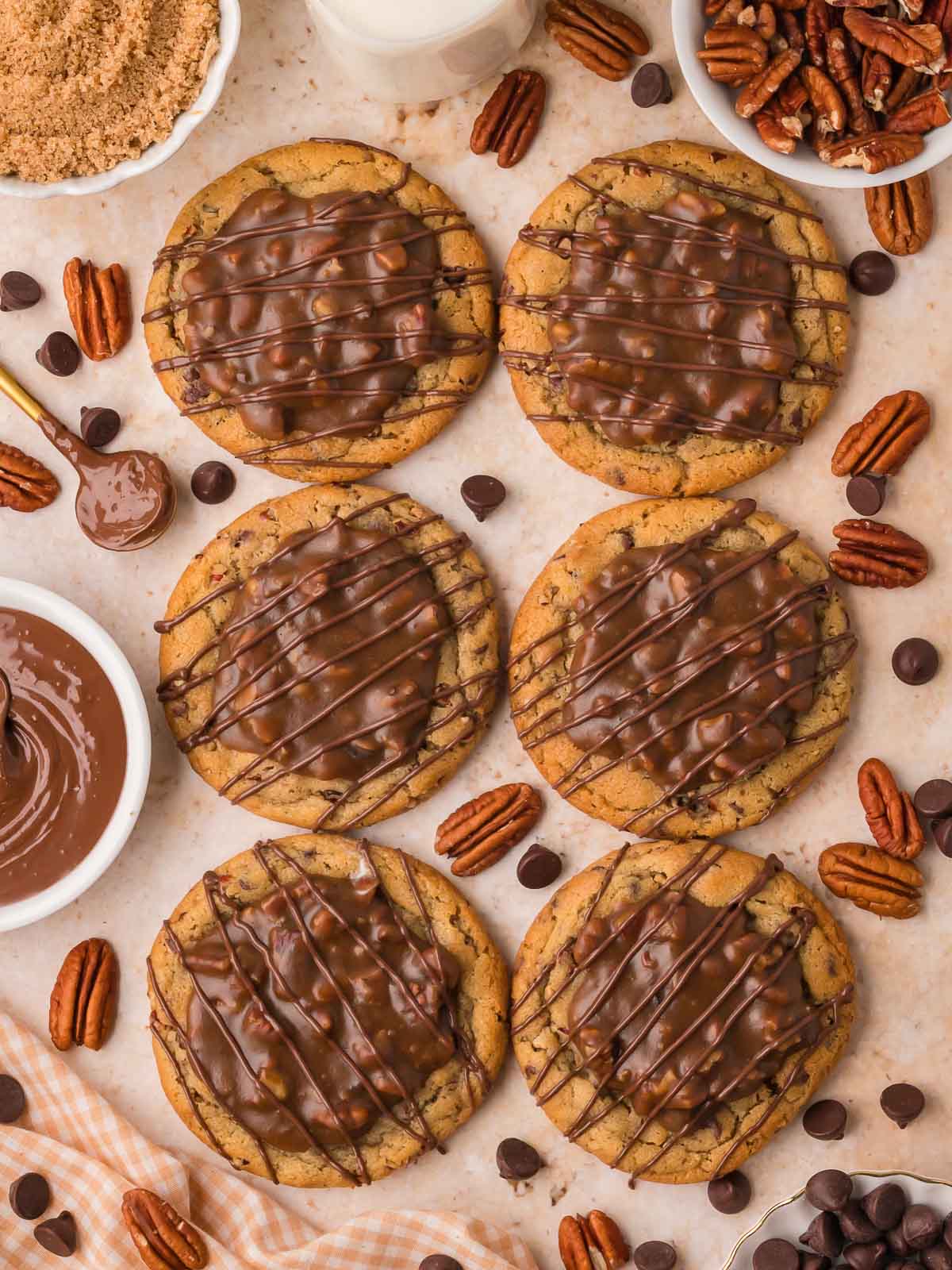 Six pecan pie cookies on parchment with brown sugar, pecans, and chocolate chips by Tessie's Table.