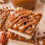Salted caramel pecan bars stacked with caramel drizzle running down the sides by Tessie's Table.