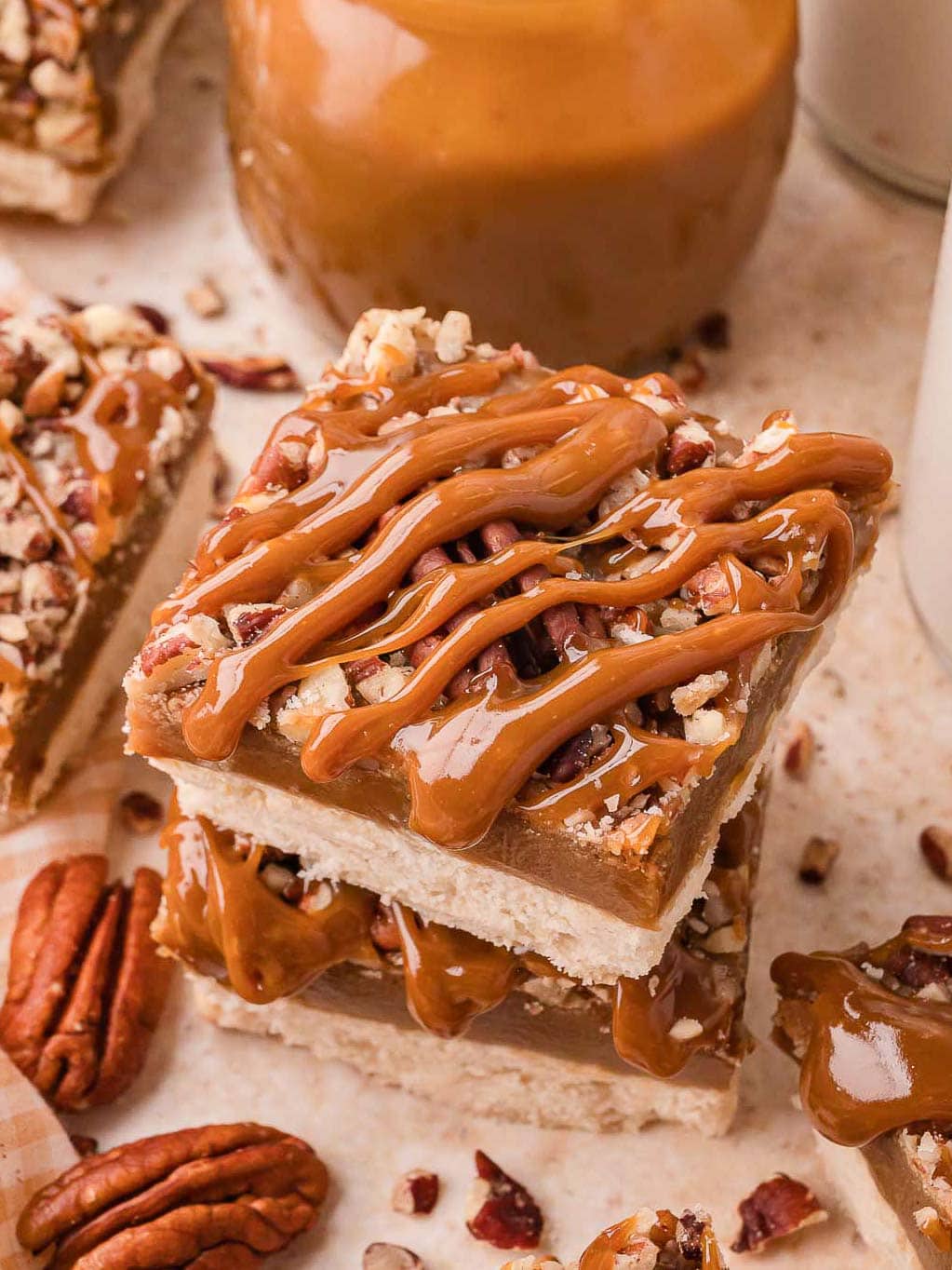 Salted caramel pecan bars stacked with caramel drizzle running down the sides by Tessie's Table.