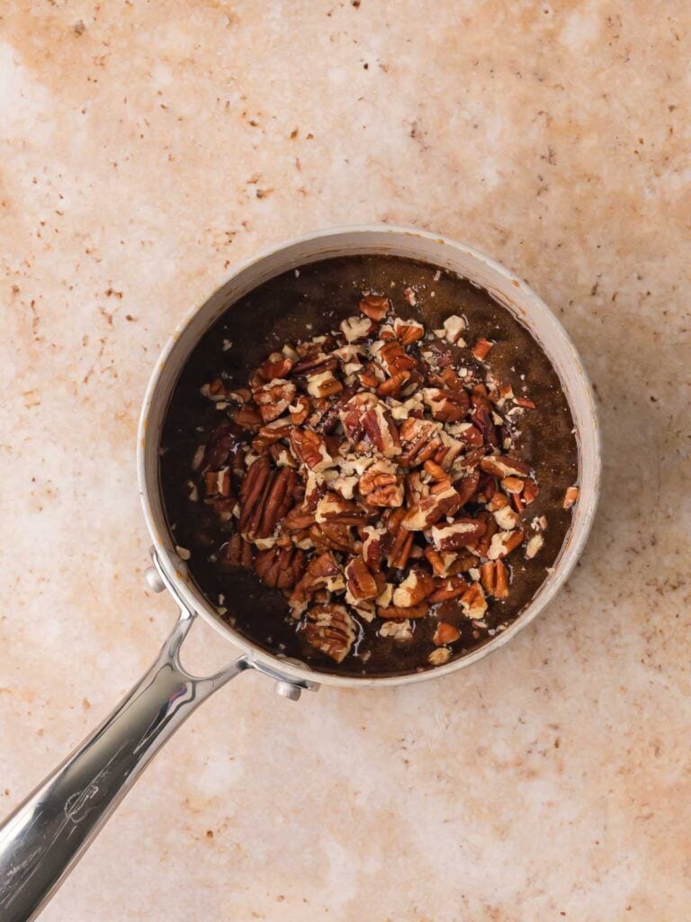 Chopped pecans stirred into brown sugar caramel in a saucepan for pecan pie cookies by Tessie's Table.