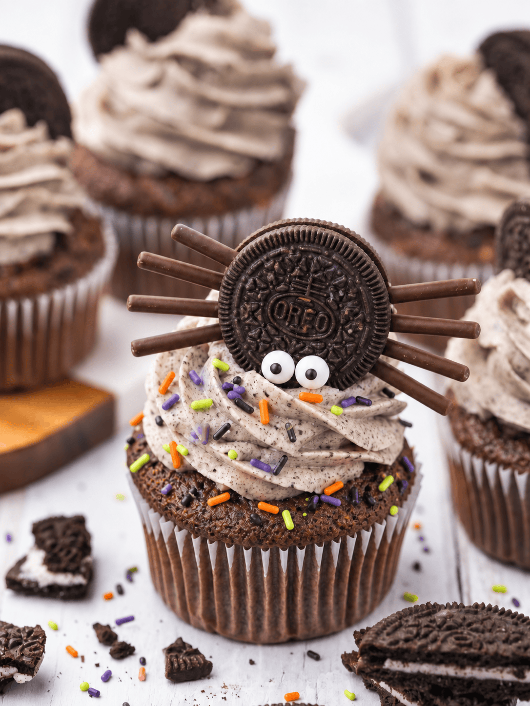 Spider Oreo cupcake for Halloween with chocolate stick legs, candy eyes, and orange and purple sprinkles.