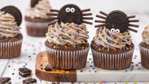 Spider Oreo cupcake for Halloween with chocolate stick legs, candy eyes, and orange and purple sprinkles.
