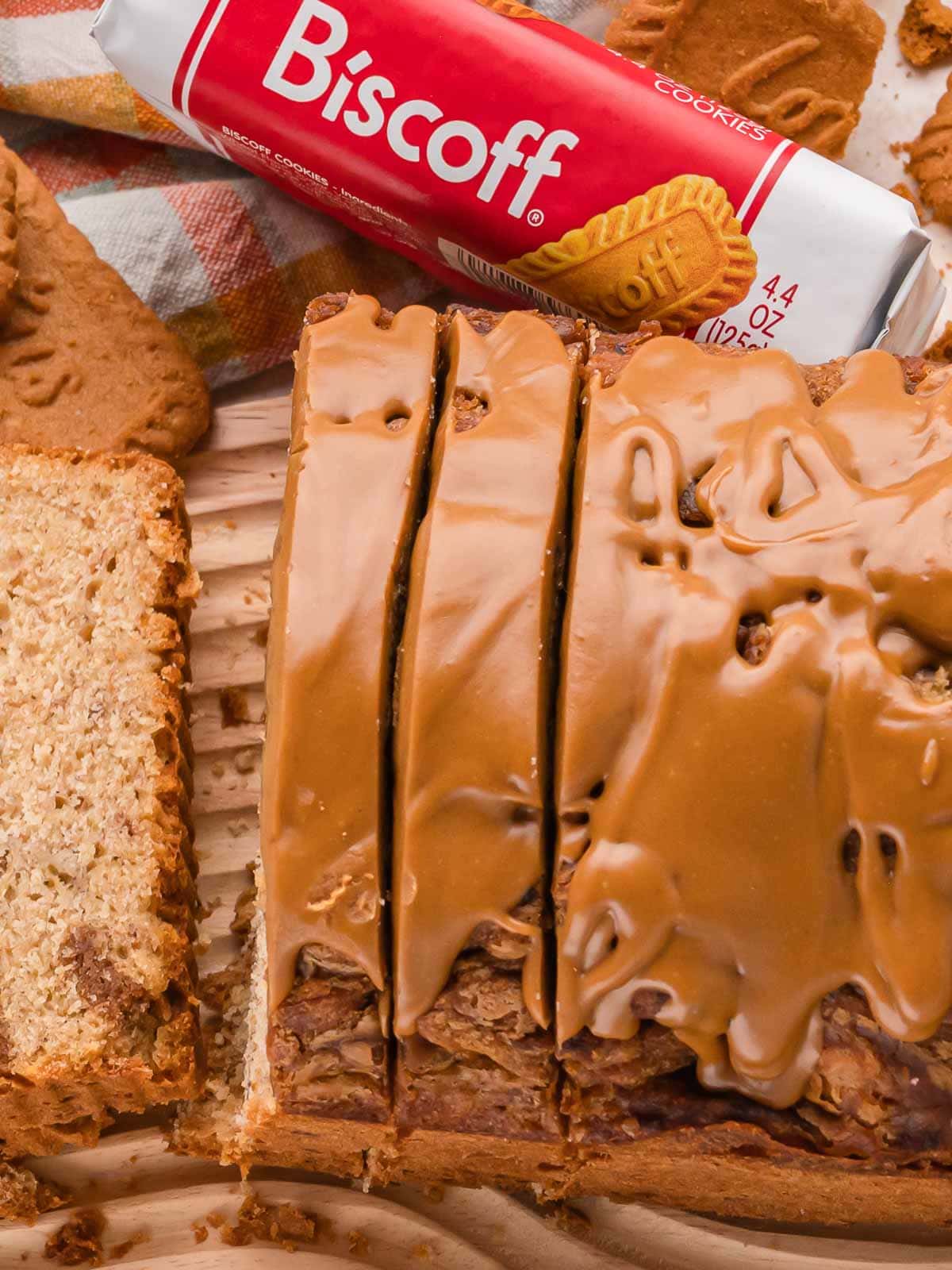 Overhead view of a sliced Biscoff banana bread loaf with a smooth cookie butter topping beside a pack of Biscoff cookies by Tessie's Table.