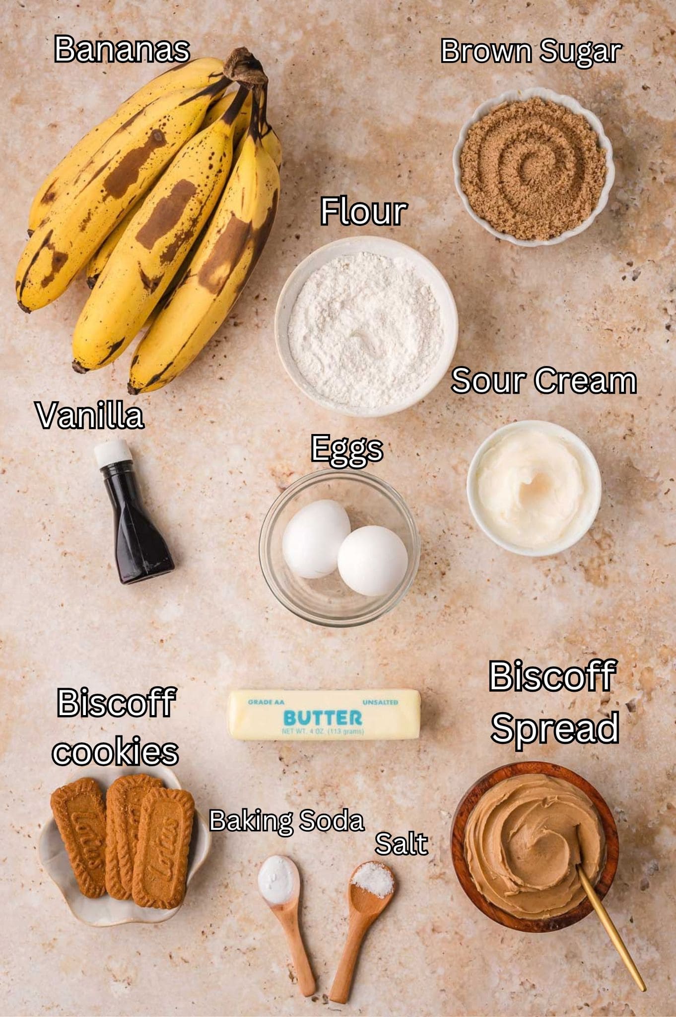 Labeled ingredients for Biscoff banana bread including ripe bananas, brown sugar, flour, sour cream, eggs, vanilla, butter, Biscoff cookies, Biscoff spread, baking soda and salt by Tessie's Table.
