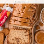 Overhead view of Biscoff banana bread with a cookie butter topping, surrounded by Lotus Biscoff cookies, a pack of Biscoff and bananas.