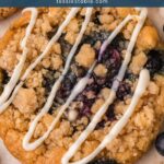 Close-up of a blueberry crumble cookie with a jammy blueberry center, crumble topping and white chocolate drizzle by Tessie's Table.