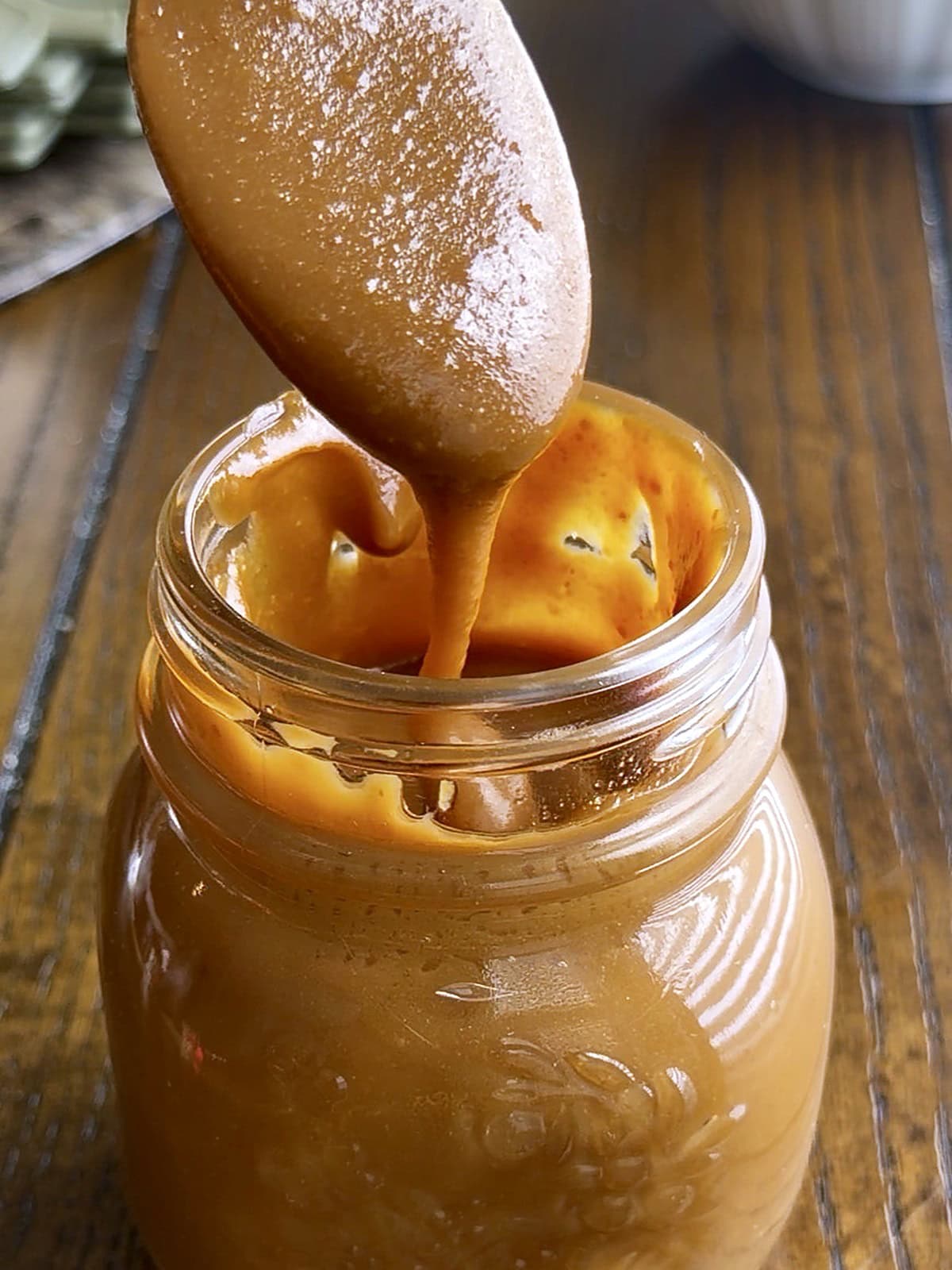 Homemade caramel with sweetened condensed milk Pinterest pin showing thick caramel sauce in a glass jar and caramel poured over shortbread bars by Tessie's Table.